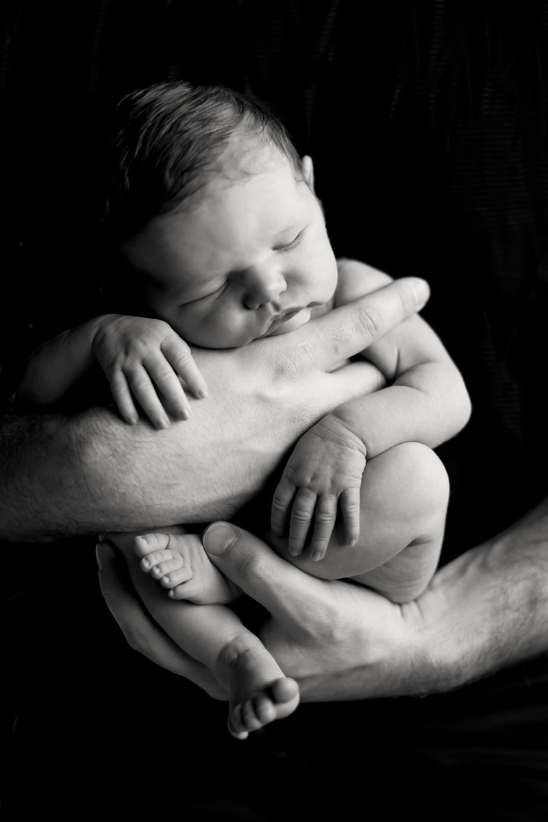 Baby Photography, black background close up of baby asleep in father's hands