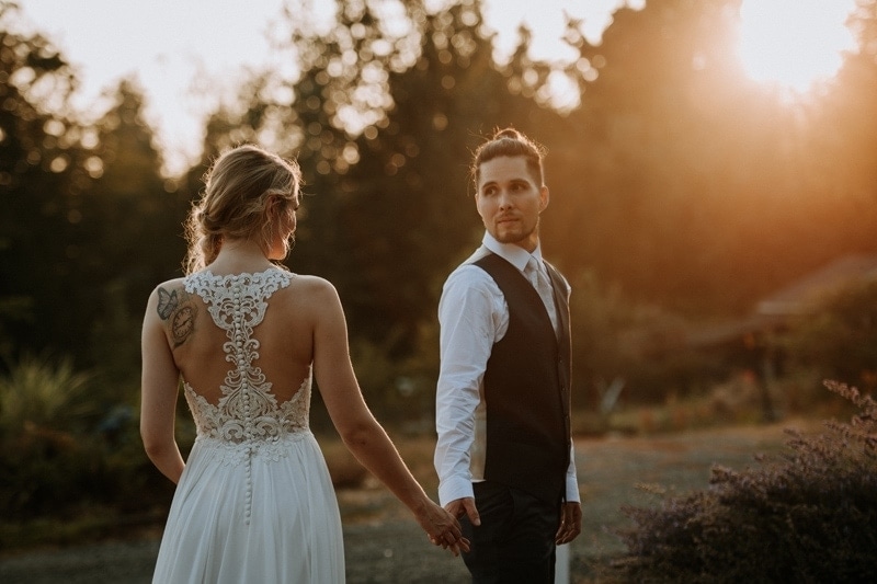 Wedding Photography, groom holding bride's hand and looking at her over his shoulder