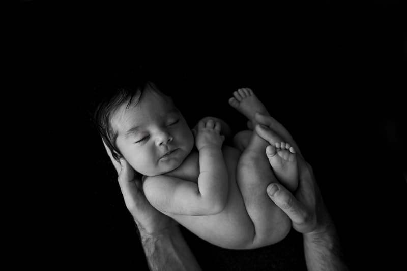 Baby Photography, baby on black background being held up by father