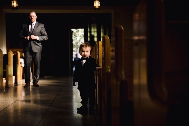 Wedding Photography, little boy standing next to a row of seats in church